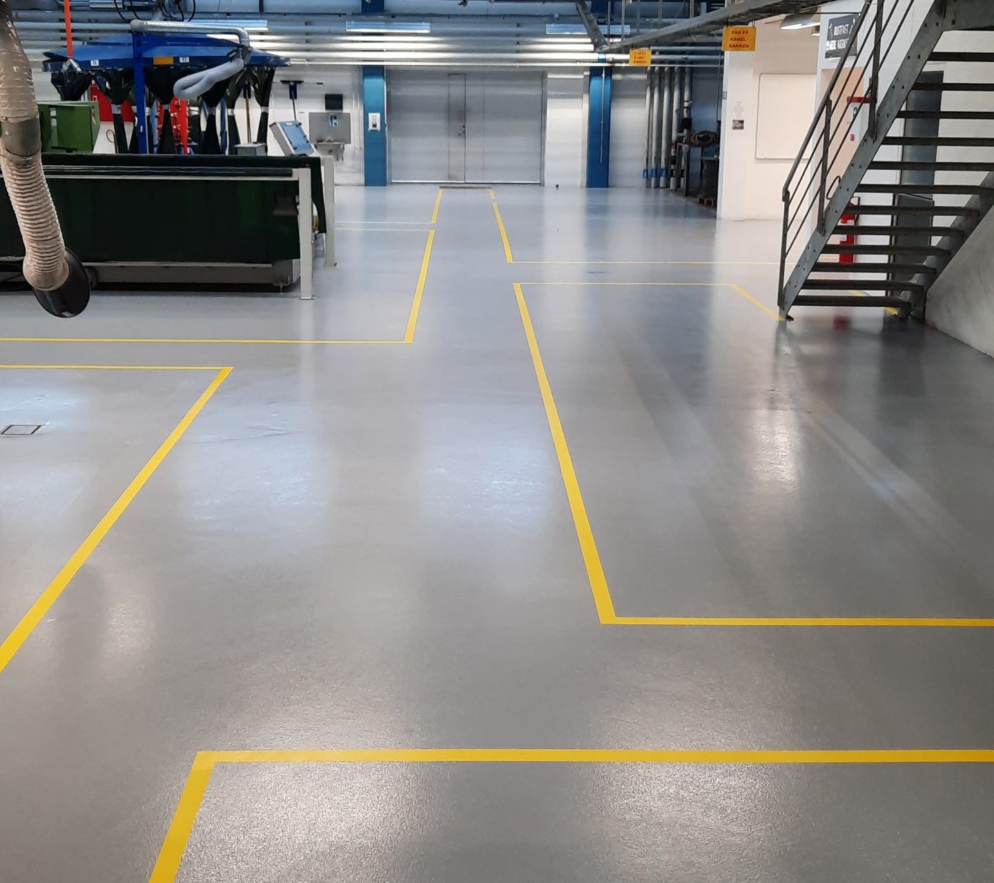 Skridsikker gråt industrigulv i stor hal med professionel, ensartet overflade.